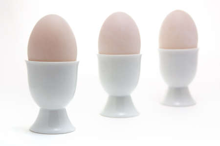 Three boiled eggs in egg cups against a white backgroundの写真素材