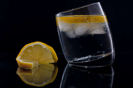 Gin and tonic or vodka and tonic with a slice of lemon over blackの写真素材