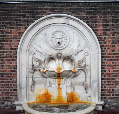 A Rust Stained Fountain Against a Brick Wallの写真素材