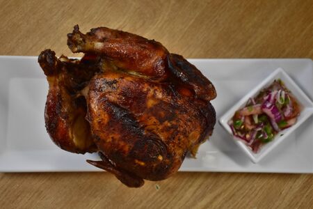 A Photograph of a Rotisserie Chicken, taken close and to the side of the plate.