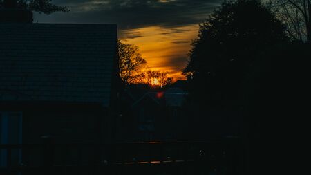 A Dark, Orange and Blue, Dramatic Sunset Over a Suburban Neighborhood that is silhouettedの写真素材