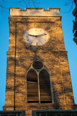 A Clock Tower on a Cobblestone Tower in a Blue Sky