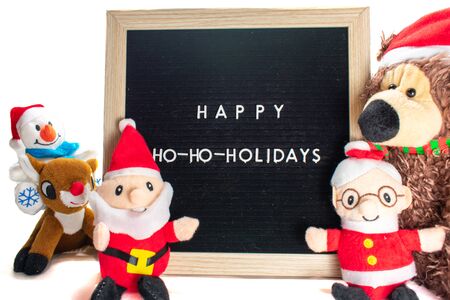A Black Sign With White Letters in a Birch Frame That Says Happy Holidays With Stuffed Christmas Animals All Around Itの写真素材