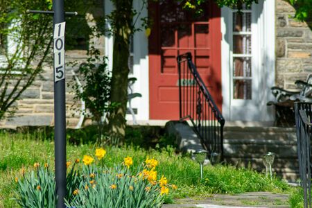 Yellow Tulips Next to a Light Post With an Address on a Front Yard With a Path Leading Up to a Red...