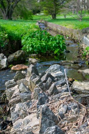 The Tip of a Fallen Cobblestone Wall With a Man-Made Creek Behind Itの写真素材