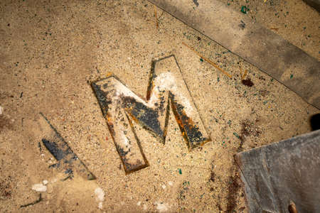 The Letter M From a Sign in an Old Abandoned Building Laying in Dust and Debrisの写真素材