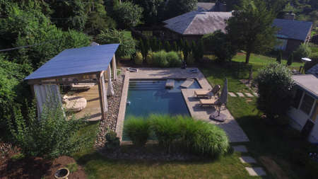 An Overhead Drone Shot of a Gorgeous Suburban Backyard With a Large In-Ground Pool and Cabanaの写真素材
