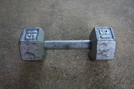 An Old Silver Fifteen Pound Weight on Concreteの写真素材