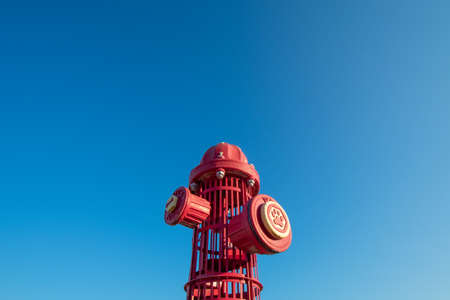 A Giant Red Fire Hydrant at a Dog Park on a Clear Sky
