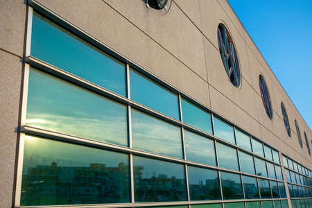 A Tan Building With a Large Window Reflecting the Sunset Skyの写真素材