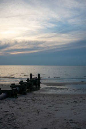 A Large Pipe With Wooden Poles on Each Side Sticking Out Into the Oceanの写真素材