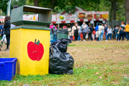A Yellow Trash Can at a Carnival With an Apple Painted on Itの写真素材