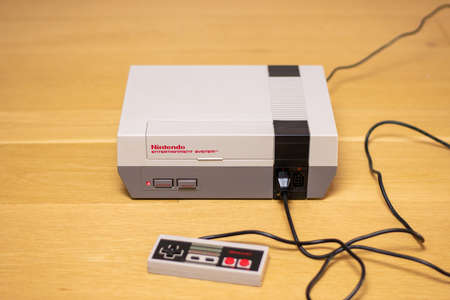 A Nintendo Entertainment System With a Controller Plugged In. The NES is a popular retro console.のeditorial素材