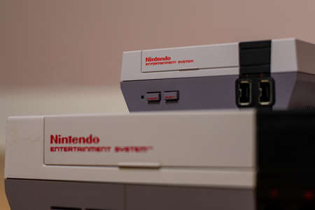 A Nintendo Entertainment System Classic Edition on Top of an Original Nintendo Entertainment System, on a wood floor. Comparison of the original NES against the NES Classic Editionのeditorial素材