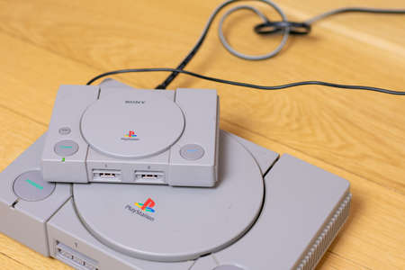 A Playstion Classic On Top of an Original Playstation, a comparison of the two, on a wood floor.のeditorial素材