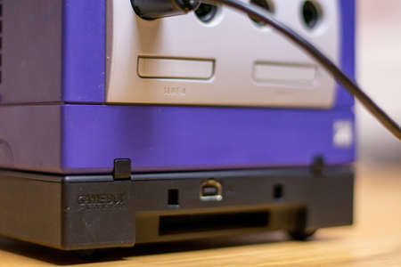 A Gameboy Player Connected to an Indigo Gamecube on a wood floor.