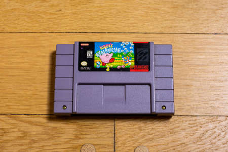 A Kirby's Avalanche Cartridge for the Super Nintendo Entertainment System on a wood floor.のeditorial素材