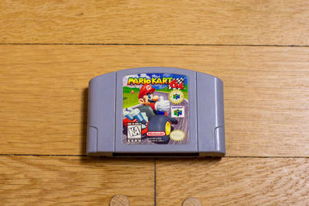 A Mario Kart 64 Cartridge for the Nintendo 64 on a wood floor.のeditorial素材