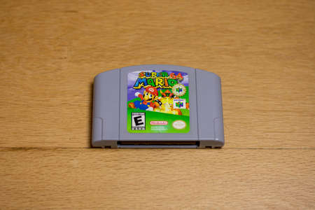 A Cartridge of Super Mario 64 for the Nintendo 64 on a wood floor.のeditorial素材