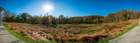 A Panoramic Shot of an Open Field on a Clear Autumn Day With the sun Behind Trees at Valley Forgeの写真素材