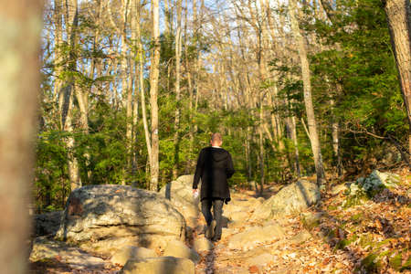 A Young Caucasian Man Wearing All Black Walking Up a Mountain Pathの写真素材