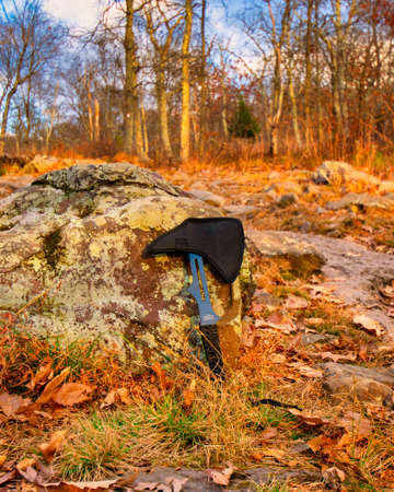 A Small Throwing Axe Leaning on a Rock in an Autumn Fieldの写真素材