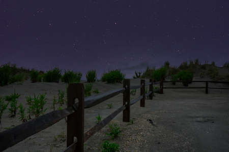 A Beach Path With a Fence on the Side and a Night Sky Full of Starsの写真素材