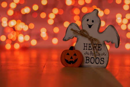 A Wood Ghost That Says Here for The Boos Next to a Jack O Lantern With Orange Bokeh Behind Itの写真素材
