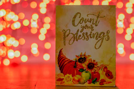 An Autumn Sign With a Cornucopia That Says Count Your Blessings With Orange Bokeh Behind Itの写真素材