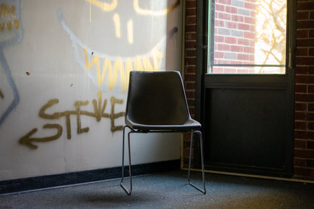 An Empty Chair Next to a Window in a Corner in an Abandoned Buildingの写真素材
