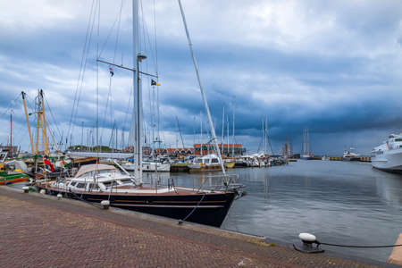 Port in the city of URK in Holland. In the harbor, boats are moored and in the background there is a blue sky with white clouds.の写真素材