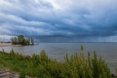 View of the sea and cloudy sky with clouds in the city of Urk in Holland. In the background are windmills.の写真素材
