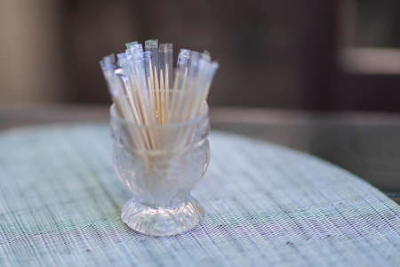 In a restaurant on a table in a glass are toothpicks laid on a white place setting. Nice bokeh.の写真素材