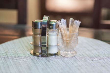 In the restaurant on the table in a glass, the toothpicks are laid on a white place setting and next to them is a salt shaker and pepper.の写真素材