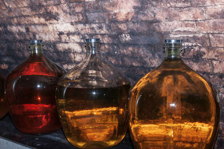 Carboys with white and red wine in the wine cellarの写真素材