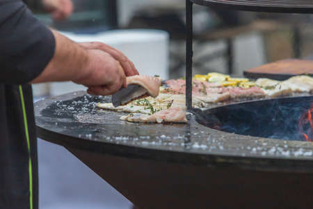 Fresh fish on the grill. A lemon wheel is placed on the fish. Fire can be seen in the middleの写真素材