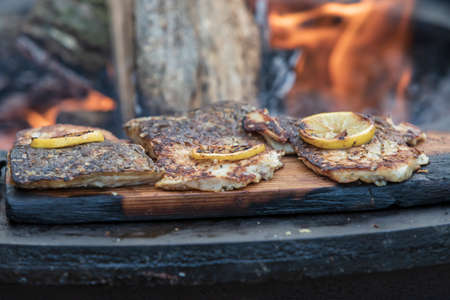 Fresh fish on the grill. A lemon wheel is placed on the fish. Fire can be seen in the middleの写真素材