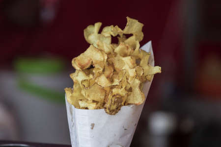 Potato spirals fried in oil in a cone for sale on the marketの写真素材