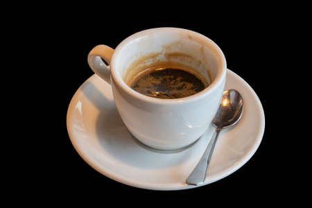 Drunk black coffee in a white mug. The cup is on a black background.