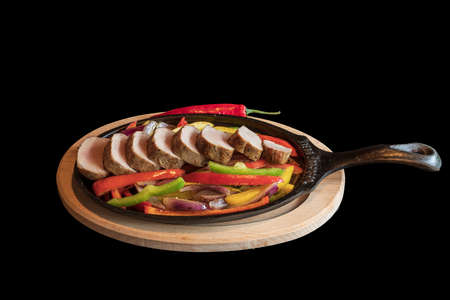 Roast pork medallions with grilled vegetables on a hot pan. The food is isolated on a black background.
の写真素材
