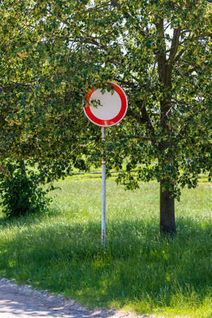 Road sign prohibiting the entry of motor vehicles, which is hidden behind tree branches.の写真素材