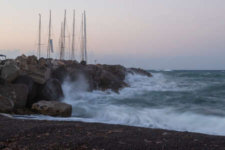 Boats in Vlichada harbor on Santorini island in Greece in the morning at sunrise. The background is...
