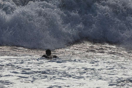 Silhouette of a surfer in the big waves of the sea.