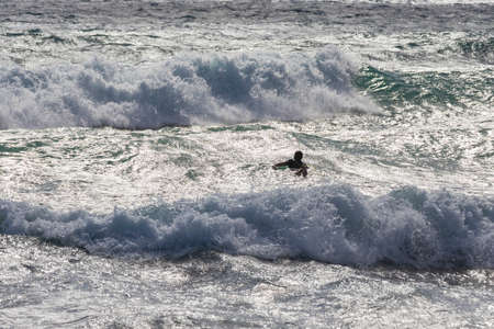 Silhouette of a surfer in the big waves of the sea.の写真素材