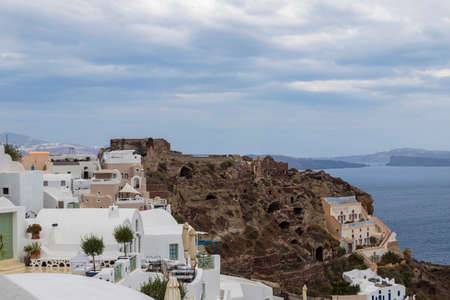 Oia town on Santorini island in Greece. The background is a blue sky with dark clouds. View of white housesの写真素材