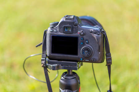 Rear view of a digital camera. The display and rear controls are visible. The camera is mounted on a...