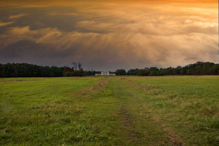 Large grassy meadow with Pohansko. There is a dramatic sky in the sky at sunrise.のeditorial素材