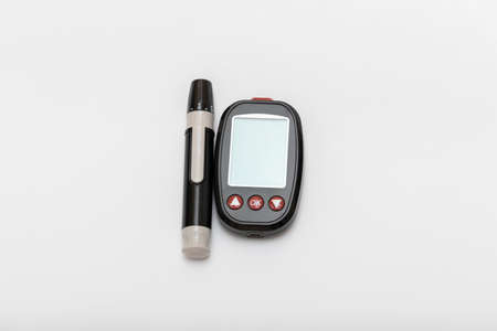 A small black glucometer with a pen and a strip for measuring blood sugar. Glucometer is isolated on a white background.の写真素材