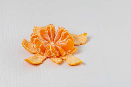 Tangerine in a split peel on a white table.の写真素材