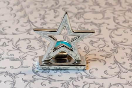 Star-shaped candlestick on a table with a patterned tablecloth.